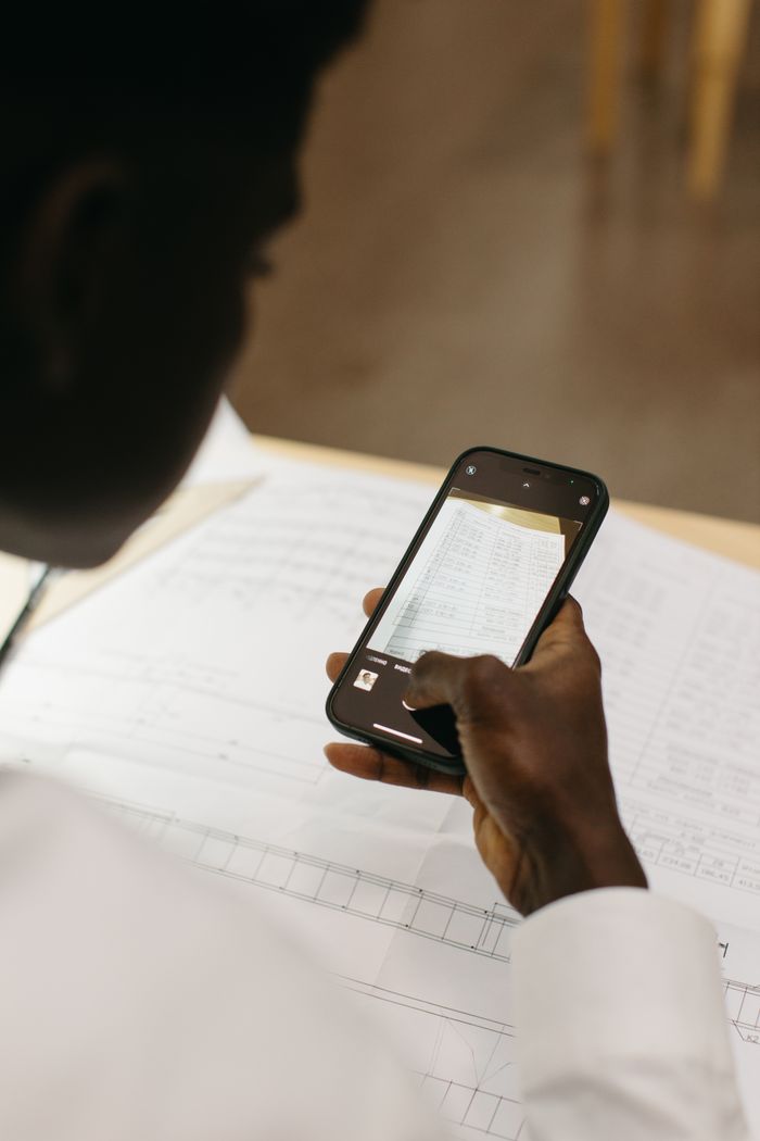 Close-up of person using smartphone to scan document, emphasizing mobile technology utilities in the workplace.